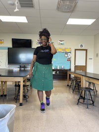 a woman in a green skirt standing in a classroom